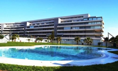 einem großen Pool vor einem Gebäude in der Unterkunft Apartamento Lujo, Primera linea playa, Garaje, Wifi, Piscina climatizada in Roquetas de Mar