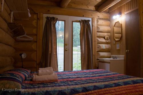 a bedroom with a bed in a log cabin at Lac Des Roches Resort in Bridge Lake