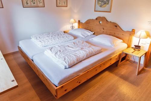 a large wooden bed with white sheets and pillows at Chesa Alvra - Celerina in Celerina