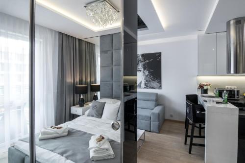 a bedroom with a bed and a desk and a kitchen at Crystal Luxury Apartments Rakowicka 22H in Krakow