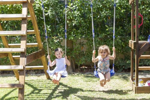 two little girls playing on swings in a yard at Anda e Rianda in Campi Bisenzio