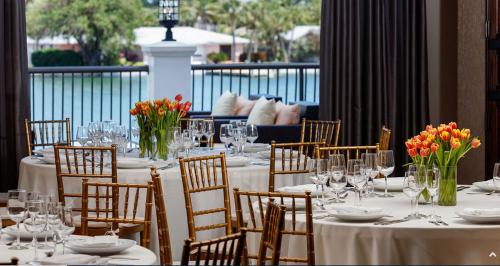 a dining room with tables and chairs with flowers on them at The Hotel Zamora in St Pete Beach