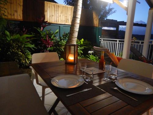 a wooden table with plates and glasses on a patio at Bungalow Anse Figuier in Terre-de-Haut