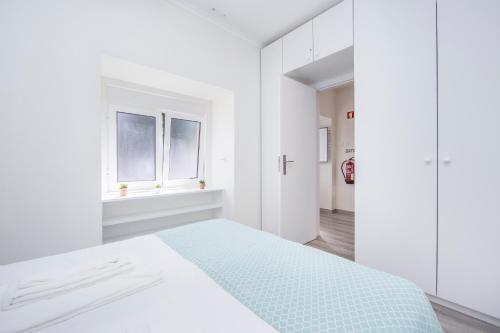 a white bedroom with a bed and two windows at FishermenApartments - Casa do Espargal in Paço de Arcos