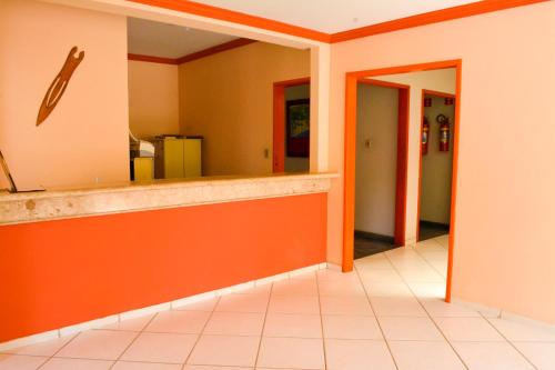 an empty lobby with orange walls and a counter at Pousada Itaúnas in Conceição da Barra