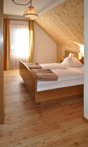 a bedroom with a large bed with a wooden floor at Panoramapension Lerchner in Bad Kleinkirchheim