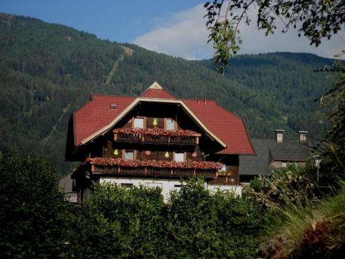 a building with a red roof with flowers on it at Panoramapension Lerchner in Bad Kleinkirchheim