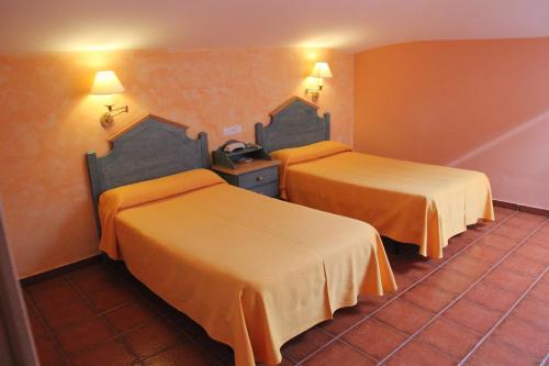 two beds in a hotel room with orange walls at Hotel Fray Tomás in Berlanga de Duero