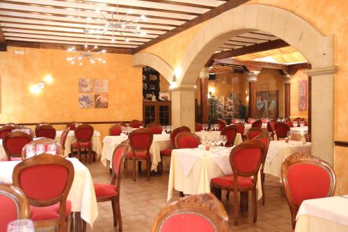un comedor con mesas blancas y sillas rojas en Hotel Fray Tomás, en Berlanga de Duero