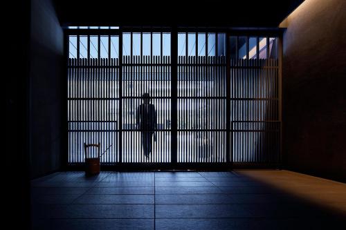 a silhouette of a person standing behind a gate at Hotel Resol Kyoto Shijo Muromachi in Kyoto