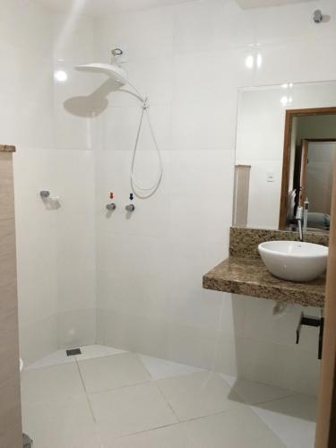 a white bathroom with a sink and a shower at Hotel Glória Barbacena in Barbacena