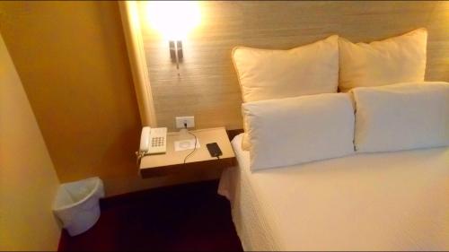 a bed with pillows and a phone on a night stand at Hotel Royal Inn in Monclova