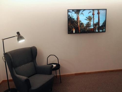 um quarto com uma cadeira e uma televisão na parede em Centro apartamentai em Druskininkai