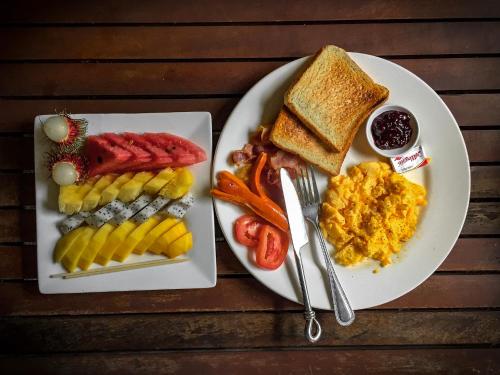un piatto di prodotti per la colazione con uova di salsiccia e pane tostato di Cocco House ad Aonang Beach