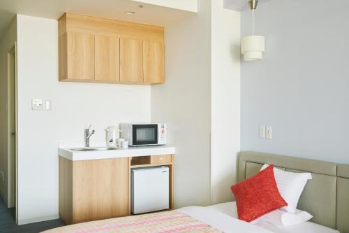 a small room with a bed and a microwave at Art Hotel Osaka Bay Tower in Osaka