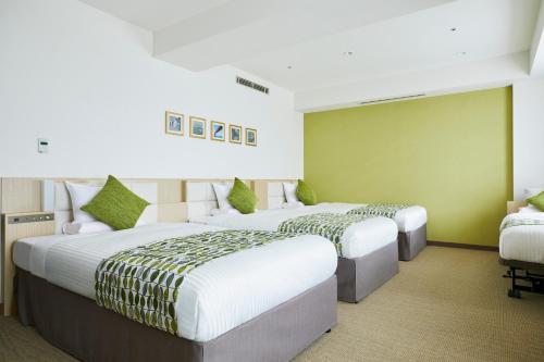 two beds in a room with green walls at Art Hotel Osaka Bay Tower in Osaka