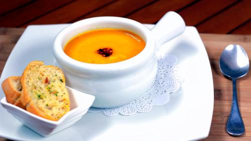 a white plate with a bowl of soup and a sandwich at La Riviera Hotel in San Antonio