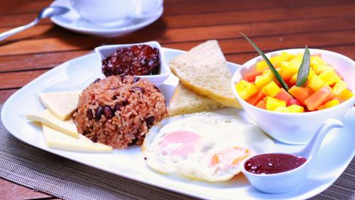 a plate of food with eggs rice and fruit on a table at La Riviera Hotel in San Antonio