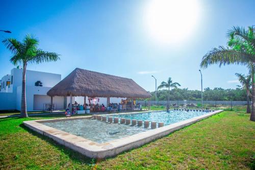 una gran piscina con una cabaña de paja en un parque en Casa Caribe Vacacional, en Playa del Carmen