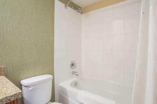 a bathroom with a white tub and a toilet and a sink at Ramada by Wyndham Williams Lake in Williams Lake