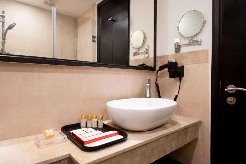 a bathroom with a white sink and a mirror at Ramada Encore Jalandhar in Jalandhar