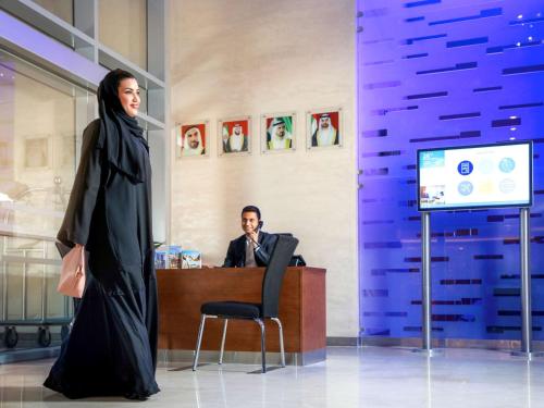a woman in a hijab standing in front of a desk at Novotel Abu Dhabi Gate in Abu Dhabi