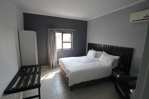 a bedroom with a bed and a window and a bench at Villa Graf in Ongwediva