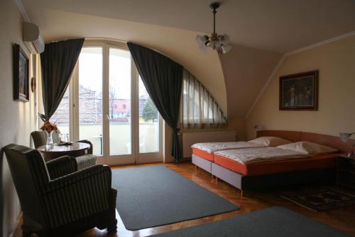 sypialnia z łóżkiem i dużym oknem w obiekcie Barokk Antik Guest Hause w mieście Kecskemét