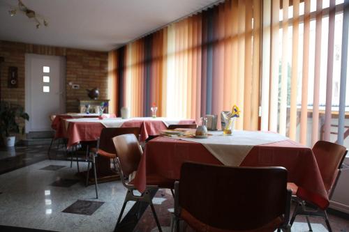 a dining room with tables and chairs with red table cloth at Barokk Antik Guest House in Kecskemét