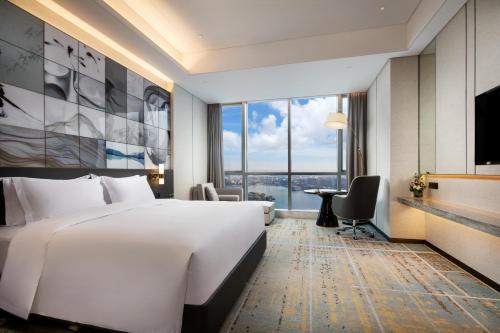 um quarto de hotel com uma cama grande e uma janela grande em Wyndham Grand Suzhou Fenhu em Xintazhen