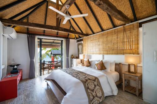 a bedroom with a bed and a ceiling fan at Amed Lodge by Sudamala Resorts in Amed