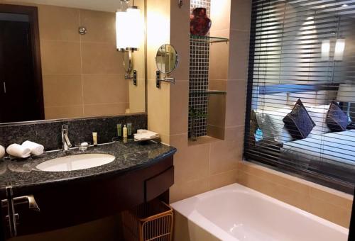 a bathroom with a sink and a tub and a mirror at Jin Jiang West Capital International Hotel the Bell and Drum Tower Muslim quarter & Metro Line 6 & indoor swimming pool & self-service free laundry room in Xi'an