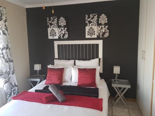 a bedroom with a large white bed with red pillows at Queens Villa Guest House in Zeerust