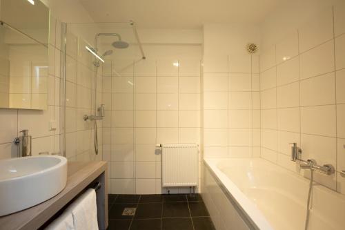 Baño blanco con bañera y lavamanos en Fletcher Hotel-Restaurant Paasberg en Lochem