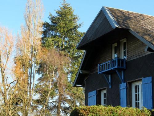 a black house with a balcony and trees at Le Chant Des Fees in Notre-Dame-de-Courson