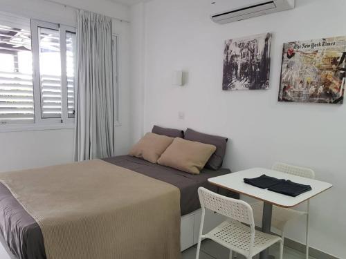 1 dormitorio con 1 cama y 1 mesa con sillas en Yialos Luxury Apartments, en Perivolia