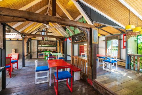 un restaurante con mesas rojas y sillas azules en Amed Lodge by Sudamala Resorts, en Amed