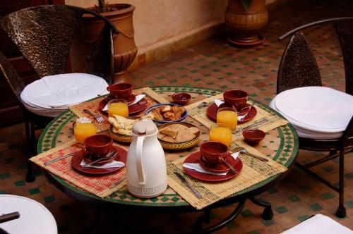 a table with breakfast foods and orange juice on it at Riad Massiba in Marrakech