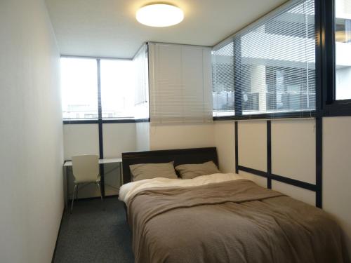 1 dormitorio con 1 cama en una habitación con ventanas en Nagoya Motoyama House A, en Nagoya