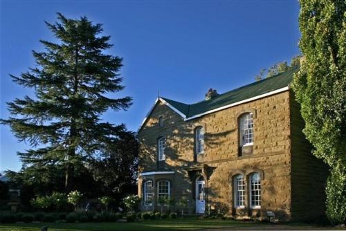 ein großes Backsteingebäude mit einem Baum davor in der Unterkunft Rose Garden Manor House in Harrismith