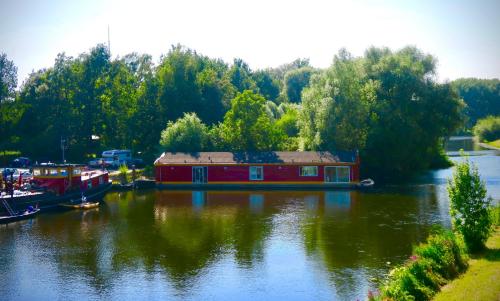 a house boat on a river with trees in the background at B&B De Leeuw in Zwolle