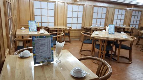 un restaurant avec des tables et des chaises en bois et des fenêtres dans l'établissement Cardogan Hotel, à Kuala Lumpur