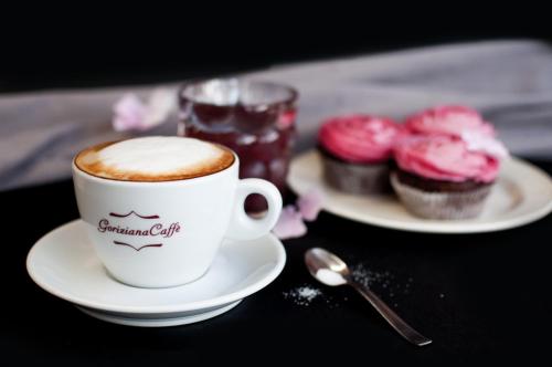 a cup of coffee and some cupcakes on a table at Hotel Mrak in Ljubljana