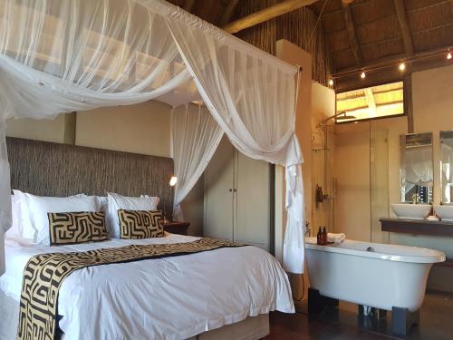 a bedroom with a bed and a bathtub and a bed and a bath tub at Tutwa Desert Lodge in Augrabies