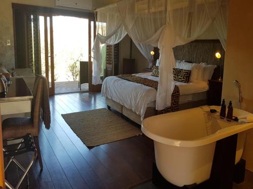 a bedroom with a bed and a tub and a sink at Tutwa Desert Lodge in Augrabies