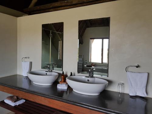 a bathroom with two sinks and two mirrors at Tutwa Desert Lodge in Augrabies