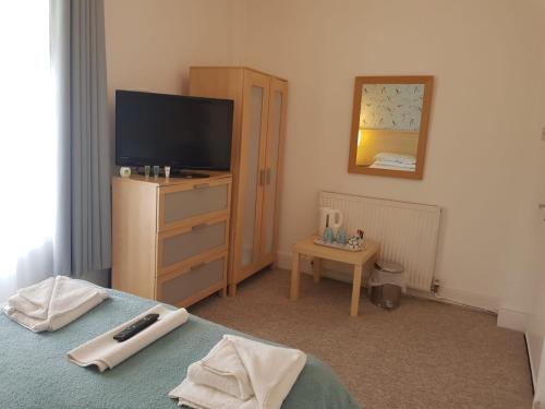 a bedroom with a bed and a tv and a dresser at St Davids Llandudno in Llandudno