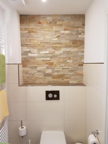 a bathroom with a toilet and a stone wall at Hotel Garni Fuhrhop in Bad Karlshafen