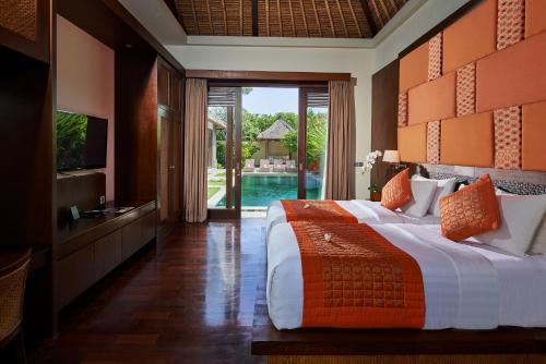 a bedroom with a bed and a television and a pool at Mahagiri Villas Sanur in Sanur