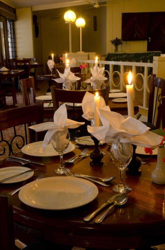 a wooden table with white plates and candles on it at Sunbird Lilongwe in Lilongwe